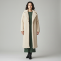 Long cream teddy coat worn open over a green ribbed knit dress, front view
